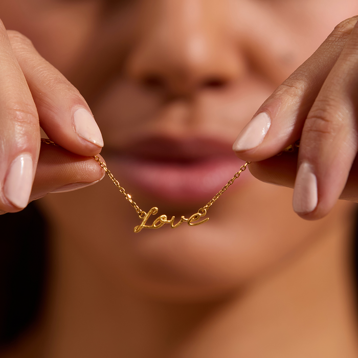 Close-up of a person holding the Adorned with Love Gold Necklace, showcasing its intricate details. This exquisite piece serves as a talisman of love and spirituality, ideal for meaningful manifestations.
