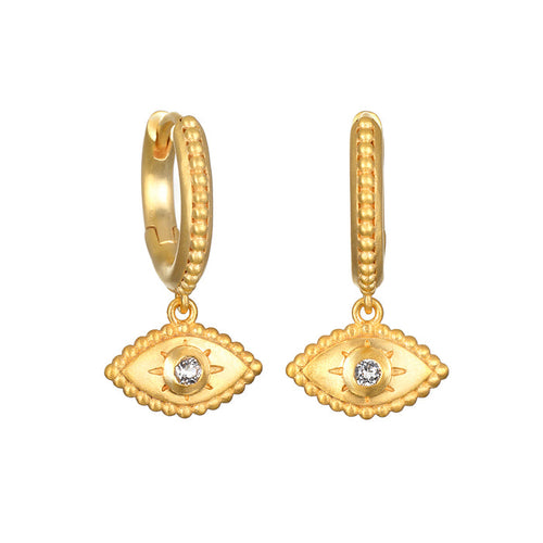 Gold huggie hoop earrings with evil eye charms featuring crystal centers and textured detailing.