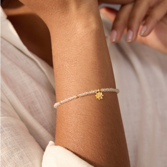 Aquamarine Lotus March Birthstone Bracelet worn on a woman's wrist, showcasing its delicate aquamarine stones and elegant gold lotus charm, ideal for yoga enthusiasts and those drawn to meaningful spiritual talismans for protection and personal growth.