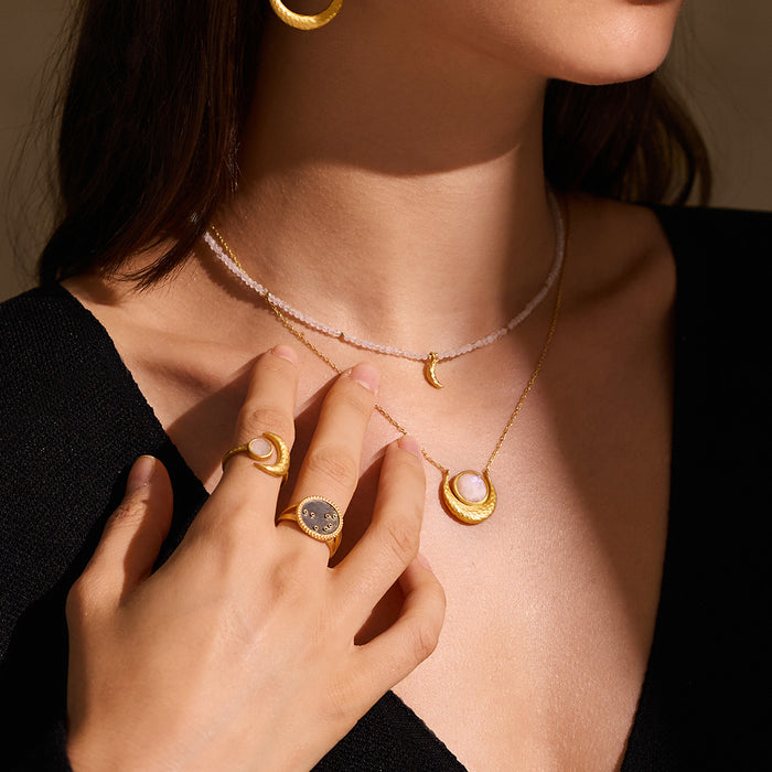 Model showcasing the Awaken Intuition Moonstone Necklace layered with other gold jewelry, representing a meaningful piece of spiritual jewelry that enhances meditation, serves as a talisman of protection and embodies the moon and sun energies in a unique fashion.