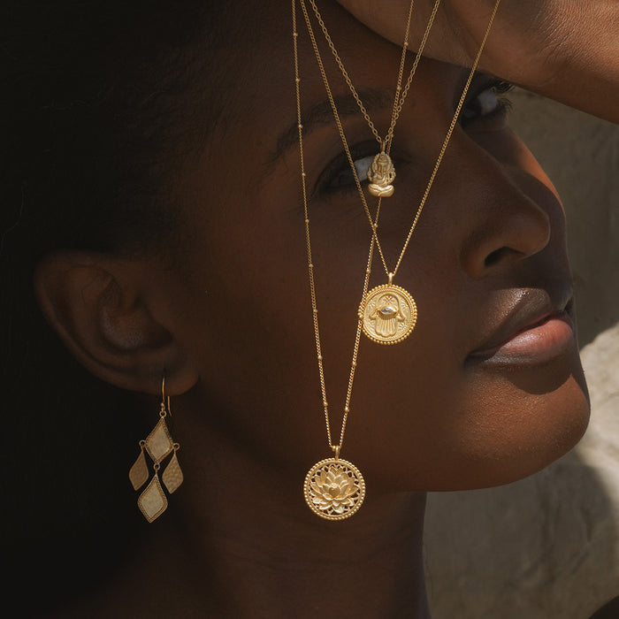 Lifestyle image featuring the Blessed Beginnings Lotus Necklace worn elegantly, alongside other spiritual jewelry, ideal for manifestation and showcasing its talisman qualities. Perfect for those seeking connection to their zodiac and meditation.