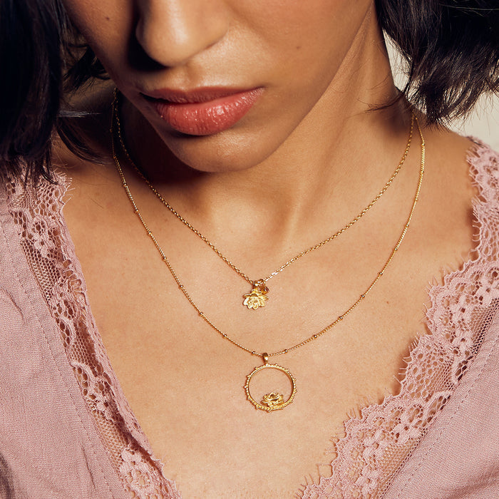 A model wearing the Bloom in Peace Lotus & Tourmaline Necklace layered with another necklace. The stunning gold plate symbolizes deep spiritual connections, perfect for meditation, yoga, and as a talisman of protection and abundance.