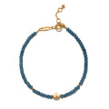 Blue beaded bracelet with gold-tone lotus charm and adjustable clasp.