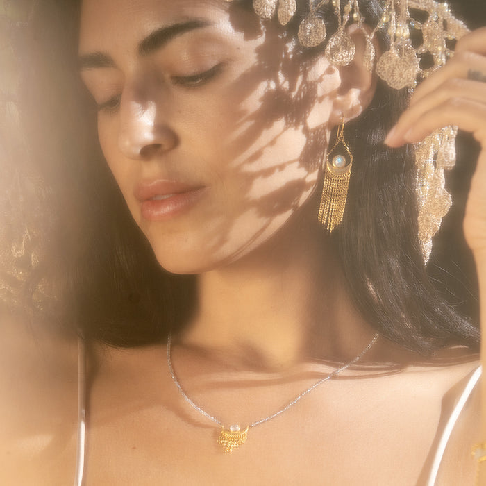 A close-up of a woman wearing the Cascade of Starlight Moonstone Fringe Drop Earrings, radiating feminine energy. The earrings symbolize the sun and moon, making them a meaningful addition to spiritual jewelry for meditation and zodiac practices.