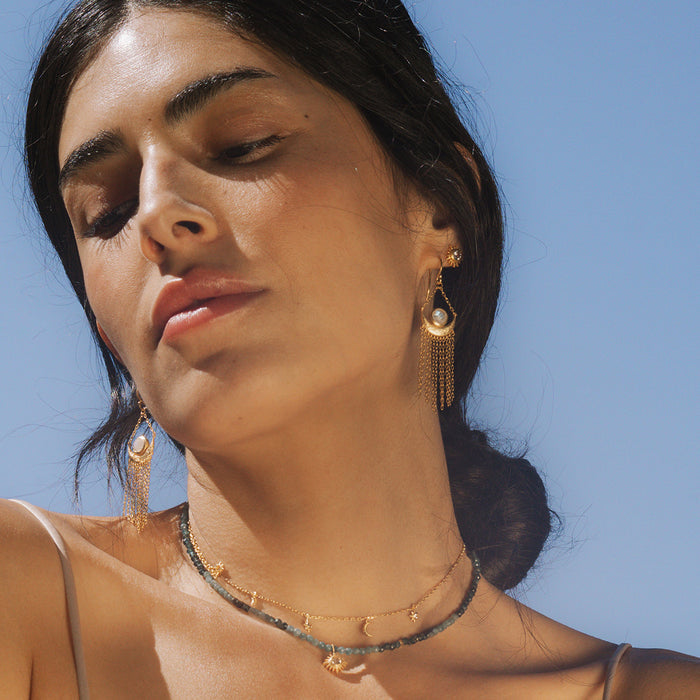 A side profile of a woman with the Cascade of Starlight Moonstone Fringe Drop Earrings, capturing the beauty of spiritual and meaningful jewelry. The design reflects the influence of the sun and moon, perfect for meditation and zodiac enthusiasts.