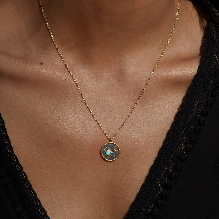 Close-up view of the Celestial Birthstone Necklace - December worn, showcasing its sun and moon pendant with turquoise detail. This zodiac-inspired spiritual jewelry serves as a protective charm for manifestation and meditation.