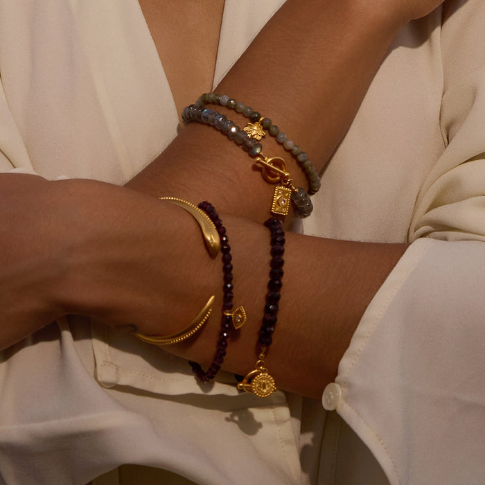 Loving Protection Garnet Evil Eye Bracelet displayed elegantly on a woman's wrist, showcasing the garnet stone and gold plate charm, exemplifying spiritual jewelry that embodies protection, meditation, and meaningful manifestation. This piece serves as a talisman for grounding energies, making it a perfect addition to yoga practice and connecting with the zodiac.
