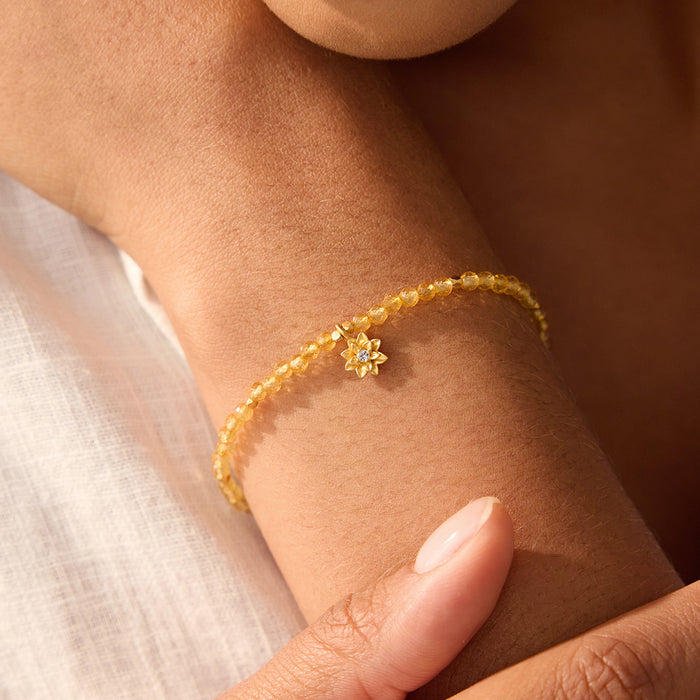 Close-up view of the Citrine Lotus November Birthstone Bracelet worn on a wrist, showcasing its elegant design with faceted round citrine and white topaz stones. This piece of spiritual jewelry serves as a radiant reminder of individuality and growth, perfect for meditation and as a talisman for those seeking meaning and connection to their zodiac. A stylish accessory for yoga practice that symbolizes happiness and protection.