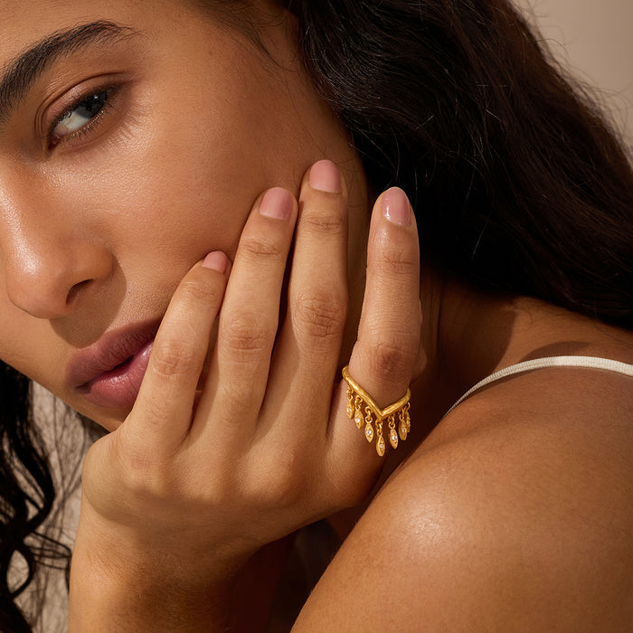 Gold ring with petal-shaped white topaz stone worn on ring finger.