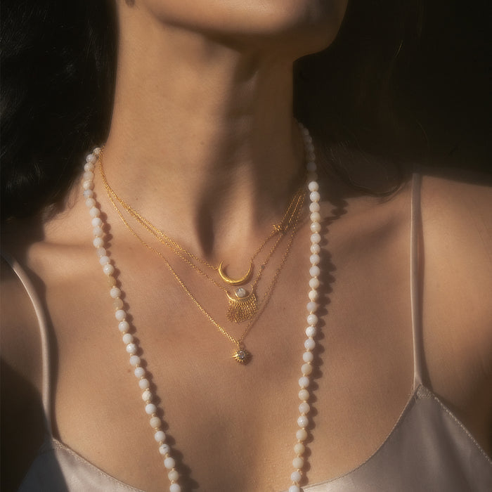 An artistic perspective of a woman adorned with the Clarity White Topaz Starburst Necklace among other beautiful jewelry pieces, highlighting its significance in spiritual practice, manifestation, and yoga.