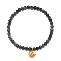 Stretch bracelet with dark blue and black faceted beads and a gold moon and sun charm pendant.