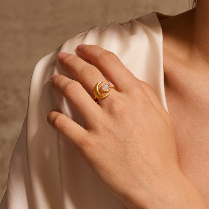 A person wearing the Cradled in Light Moonstone Ring, showcasing its elegant design against a soft fabric. This spiritual jewelry piece represents the balance of sun and moon, making it a perfect talisman for meditation and meaningful connections in your yoga practice.