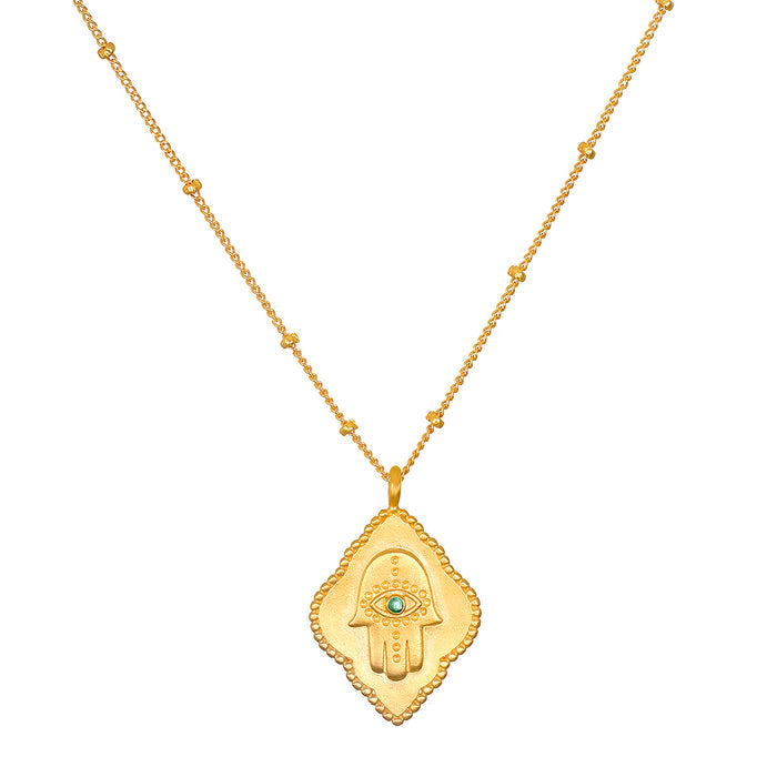 Cradled in Protection Gold Hamsa Necklace, an intricately designed spiritual jewelry piece symbolizing protection and blessings. This talisman features a hamsa hand with an evil eye and emerald gemstone, making it a meaningful charm for meditation and manifestation in your yoga practice. Perfect for those who resonate with zodiac energies, this necklace embodies the essence of sun and moon, enhancing your spiritual journey.