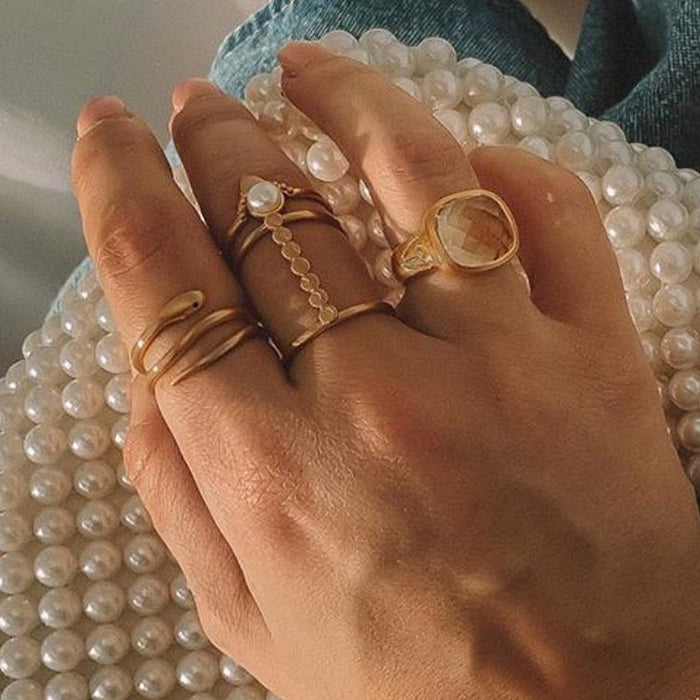Hand adorned with various rings including the Cycles of the Goddess Adjustable Gold Ring, blending spiritual jewelry styles for a fashionable look. These talismans serve as protection and meaning, resonating with those who practice meditation and seek deeper connections with the sun and moon.