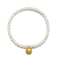 Stretch bracelet with white mother of pearl beads and gold-tone sun charm pendant.