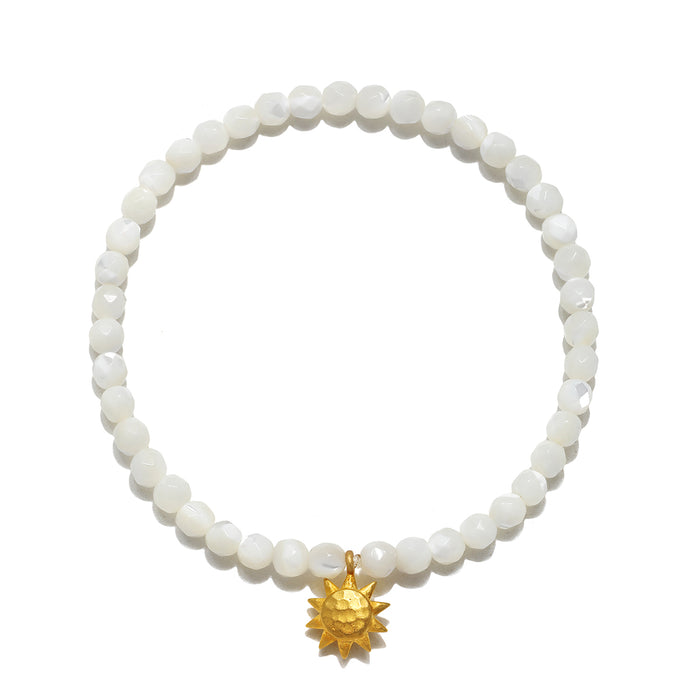 Stretch bracelet with white mother of pearl beads and gold-tone sun charm pendant.