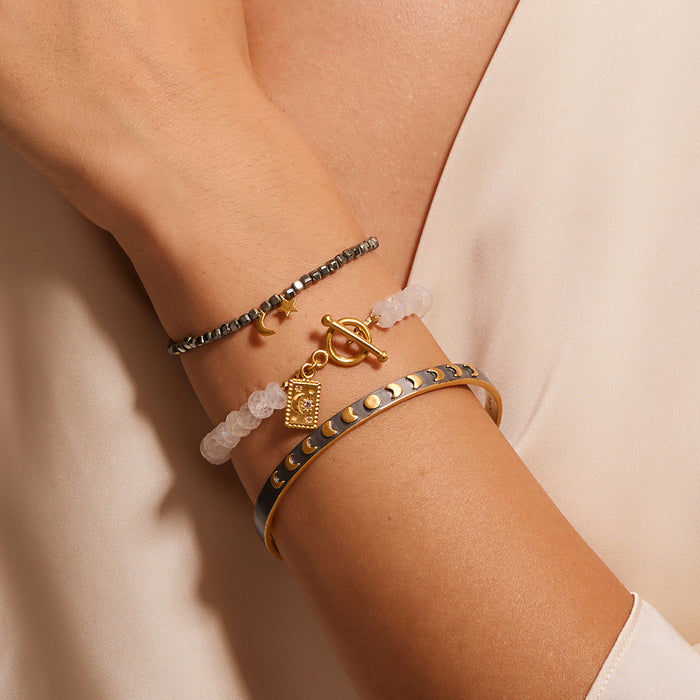 A close view of the Spiritual Evolution Moon Phase Cuff worn alongside other bracelets. This unique piece represents spiritual meaning, protection, and the connection between the sun and moon, enhancing your meditation and zodiac journey.