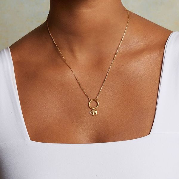 A close-up of a person wearing the Elephant Mini Charm on a delicate gold necklace. This spiritual jewelry piece embodies meaning and serves as a talisman for those who appreciate protection, meditation, and connection to the sun and moon energies in their yoga practice.