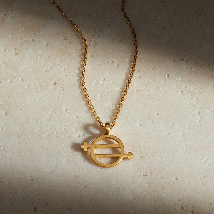 The Equal Means Equal necklace displayed elegantly on a textured surface, showcasing its symbolic gold charm that represents equality. This meaningful piece of spiritual jewelry is perfect for meditation, yoga, and a reminder of sacred values, making it an ideal manifestation gift.
