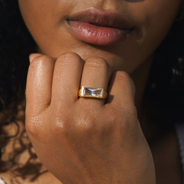 A close-up of the Eternal Radiance White Topaz Ring worn on a woman's finger, reflecting sunlight, symbolizing individuality and creativity. This piece from Satya Jewelry embodies spiritual jewelry, perfect for meditation and manifestation, with a design that resonates with the meanings of sun and moon, enhancing your spiritual journey.