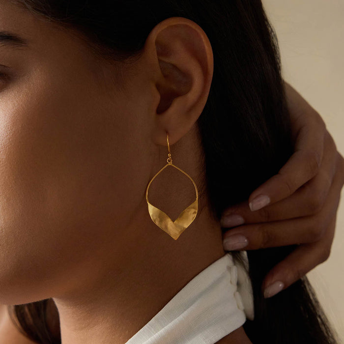 A model wearing Fluttering Petals Gold Earrings that elegantly accentuates her style. These earrings embody the essence of spiritual jewelry, blending fashion with meditation and the significance of talismans. Perfect for yoga enthusiasts and those interested in zodiac meanings and manifestation.
