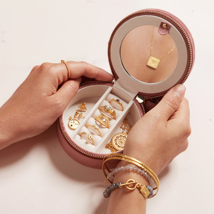 Hands holding the For the Journey Travel Jewelry Case filled with beautiful rings and charms, illustrating storage for meaningful jewelry that enhances spiritual connection and protection during your yoga journey.