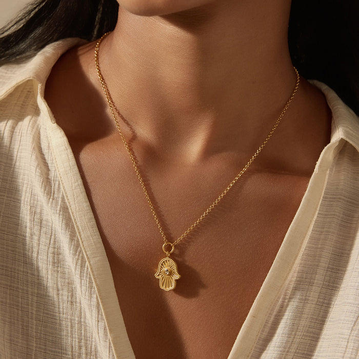 Close-up of a model wearing the Gaining Clarity White Topaz and Mother of Pearl Hamsa Reversible Necklace, illustrating its role as a spiritual talisman. This exquisite jewelry piece symbolizes protection and meaningful meditation, perfect for those embracing their spiritual journey under the sun and moon.