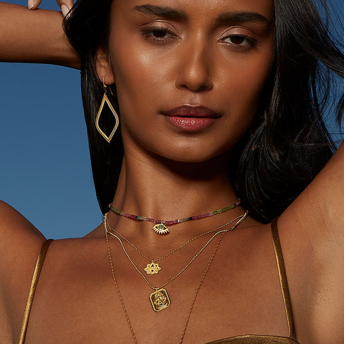 Model wearing Ganesha Hindu God, Bestower of Good Fortune Necklace alongside other spiritual jewelry. The delicate design complements the themes of zodiac and meaning, making it an ideal charm for meditation and personal empowerment.