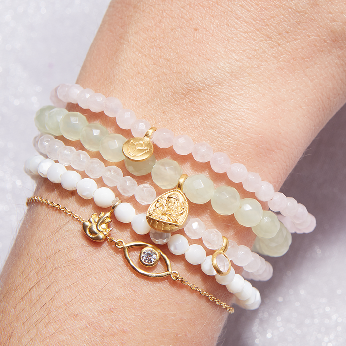 A close-up view of a hand adorned with the Ganesha Hindu God Pearl Gemstone Bracelet and other complementary bracelets. This beautiful piece of spiritual jewelry symbolizes protection and meaningful transformations, perfect for meditation and yoga practices. The bracelet carries a sense of sacred significance and is ideal for manifestation of intentions through the mantra associated with Ganesha.