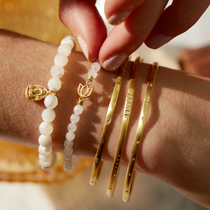Close-up of the Gold Melody Bracelet Bangle alongside other bracelets, emphasizing its protective and sacred qualities in the context of mantra and spiritual jewelry.