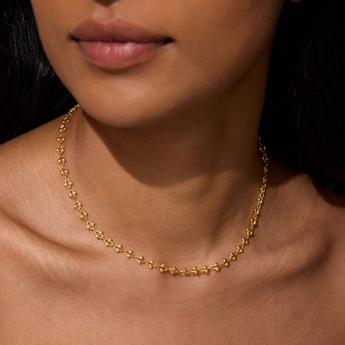 A close-up of a model wearing the Golden Hour Coin Chain Necklace, showcasing its elegant 16" length with a 3" extender. This stylish piece of spiritual jewelry enhances your yoga practice, representing the sun and moon's balance in spiritual meaning and manifestation.
