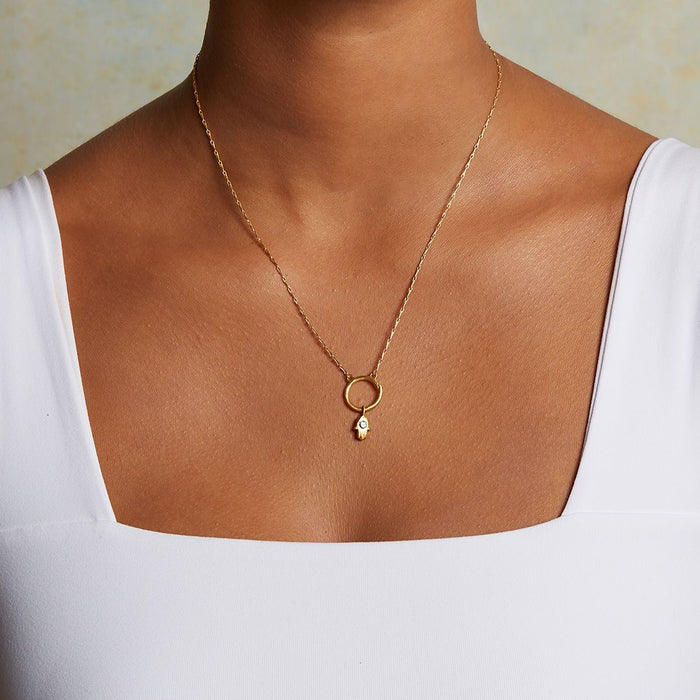 A model wearing the Hamsa Labradorite Charm on a delicate gold necklace, embodying spirituality and protection. This meaningful charm connects with the sun and moon energies, making it a beautiful talisman for zodiac enthusiasts and those seeking deeper meditation and manifestation.