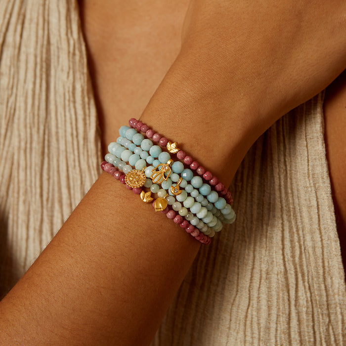 Healing Journey Rhodonite Stretch Bracelet worn on a wrist, showcasing its beautiful pink rhodonite beads and golden lotus flower charm. This piece is perfect for spiritual jewelry, meditation, and as a protective talisman, ideal for yoga and manifestation practices.