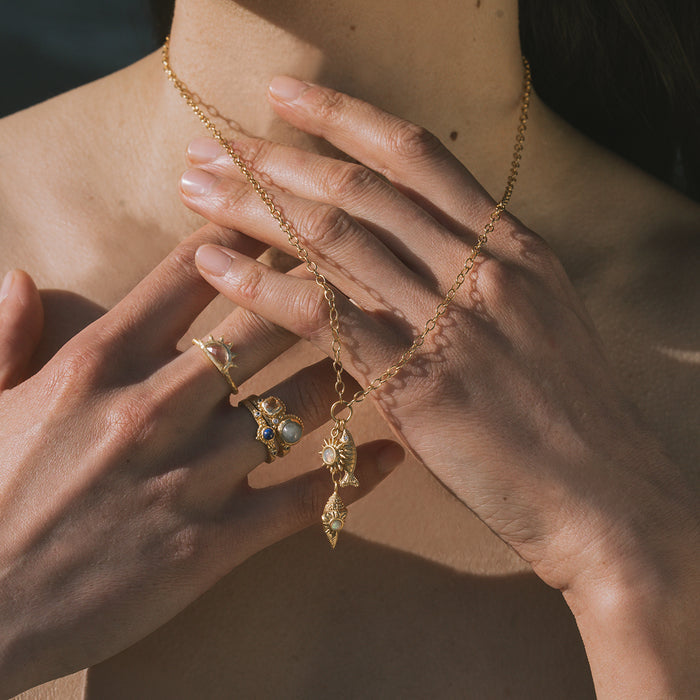 Gold-tone necklace with decorative pendant charms worn around neck on person's chest.