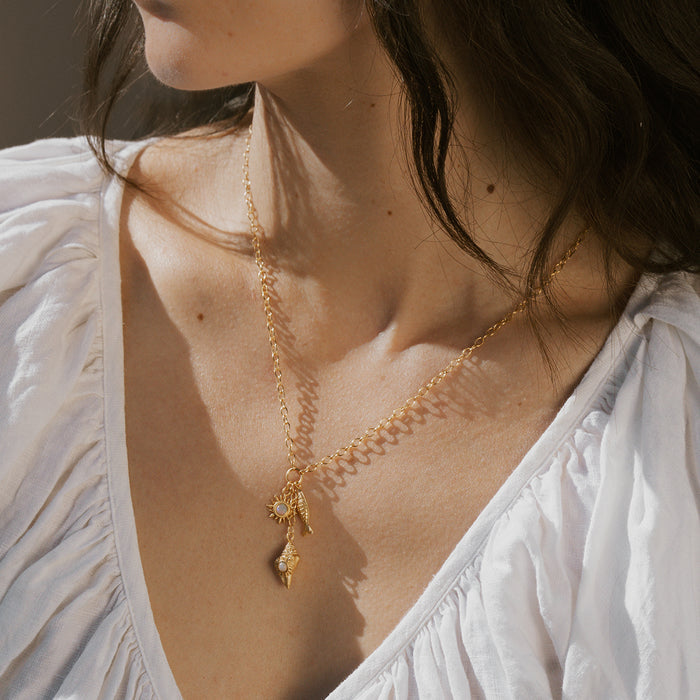 Gold chain necklace with shell and starfish charms hanging from delicate links.