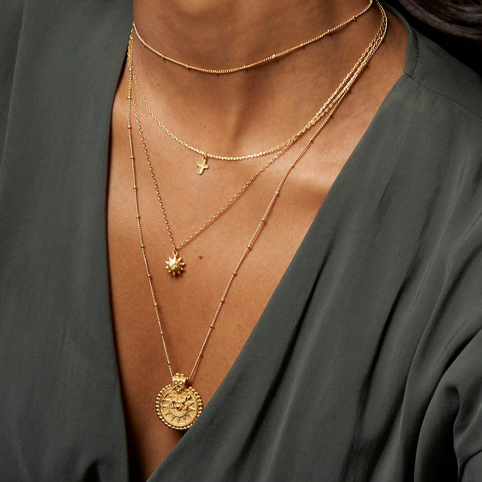 Model showcasing the Here Comes the Sun Necklace layered with other delicate gold chains, representing the sun's vitality as part of a spiritual jewelry collection. This combination highlights elements of meditation, protection, and meaningful adornments for those who align with the sun's powerful manifestation energy.