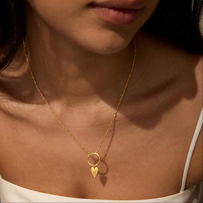 A model wearing the Infinitely Loved Heart Charm necklace, showcasing the gold heart charm resting elegantly on the collarbone. This spiritual jewelry piece serves as a talisman for manifestation and protection, ideal for meditation and yoga practices, embodying the essence of love, meaning, and personal growth.
