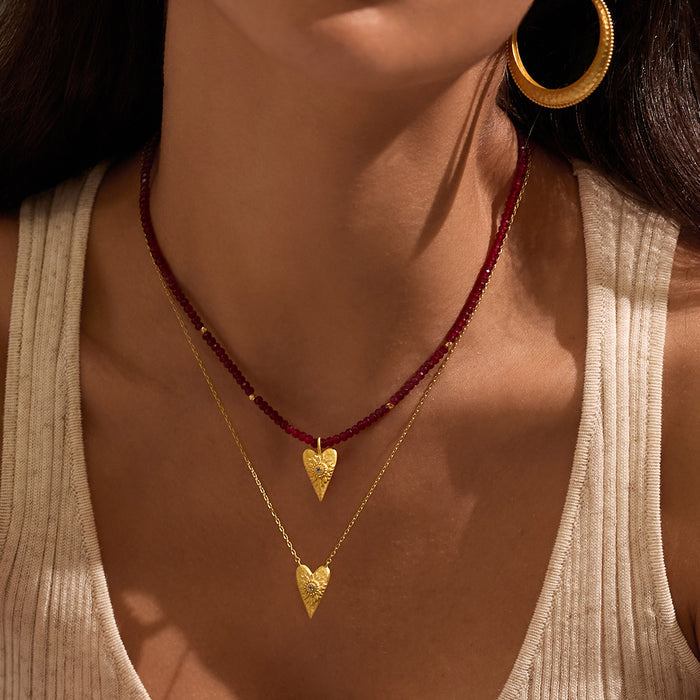 Model wearing the Infinitely Loved Heart Necklace layered with a red beaded necklace, showcasing the spiritual jewelry's design and connection to meditation and meaningful manifestation.