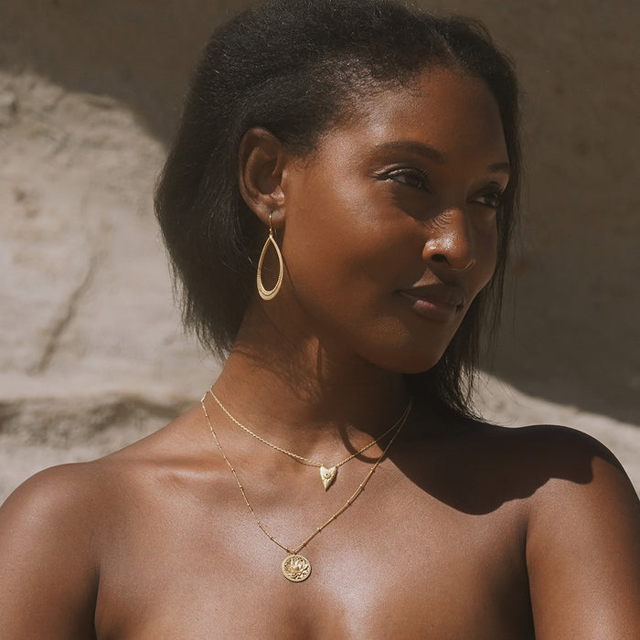 Close-up of the model wearing the Infinitely Loved Heart Necklace and a unique earring, exemplifying spiritual jewelry that embodies protection and the essence of zodiac energies.