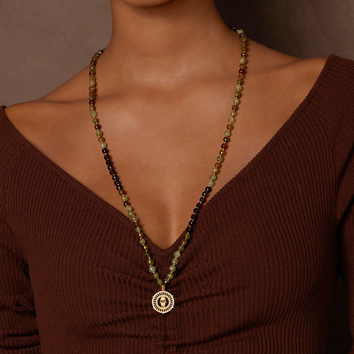 Inhabit Your Power Smokey Quartz Green Garnet Mala worn as a stylish necklace, showcasing its unique design made of smokey quartz and green garnet beads. This spiritual jewelry serves as a talisman for meditation and manifests protection, perfect for yoga enthusiasts and those who value meaningful adornments.