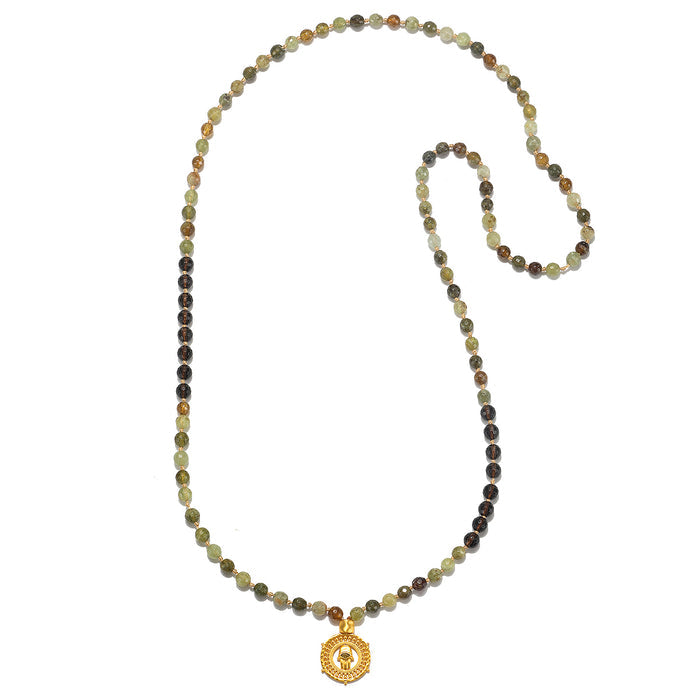 The Inhabit Your Power Smokey Quartz Green Garnet Mala elegantly displayed on a flat surface, highlighting its vibrant smokey quartz and green garnet beads. This mala is a beautiful piece of spiritual jewelry, ideal for meditation and personal manifestation, and a perfect talisman for connecting with the sun and moon.