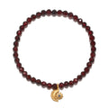 Stretch bracelet with faceted dark red garnet beads and gold-tone moon and sun charm pendant.