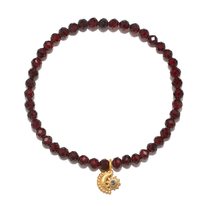 Stretch bracelet with faceted dark red garnet beads and gold-tone moon and sun charm pendant.