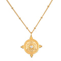 Gold chain necklace with circular mandala pendant featuring white topaz center stone and four decorative gold terminals.