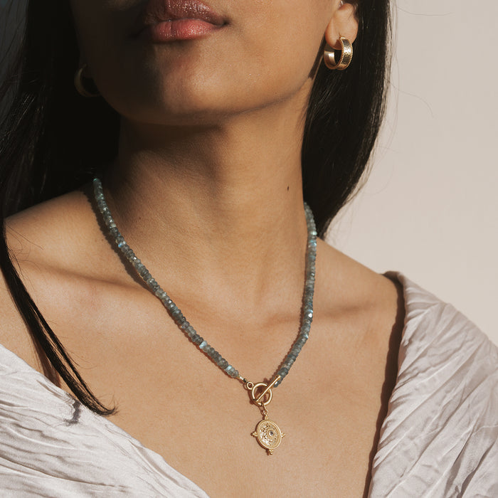 Gray labradorite beaded necklace with gold-tone toggle clasp and circular mandala pendant.