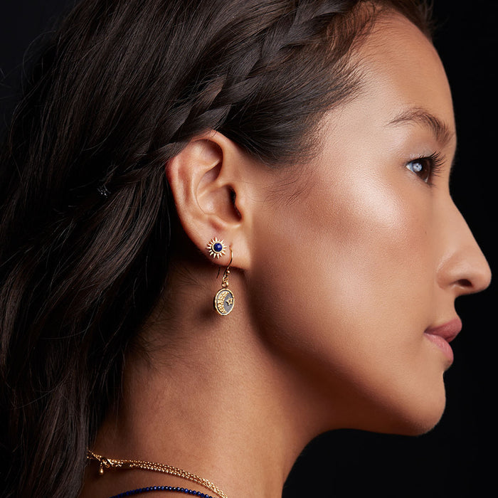 A woman showcasing the Light Seeker Lapis Starburst Earrings, embodying spiritual jewelry and manifestation energy. The stunning earrings reflect the sun and moon, perfect for yoga practices and meditation, representing power, protection, and the meaning of vitality.
