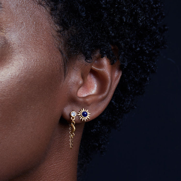 Close-up of the Light Seeker Lapis Starburst Earrings worn by a person with curly hair. This spiritual jewelry serves as a talisman for protection and connection to zodiac energies, ideal for meditation and meaningful adornment.