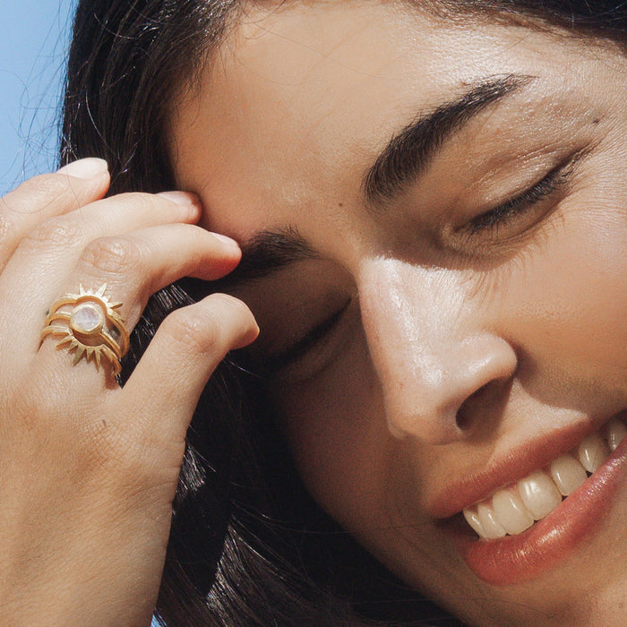 Close-up of the Light Seeker Moonstone Starburst Nested Ring Set on a smiling model, representing a blend of sun and moon symbolism in spiritual jewelry, perfect for manifestation and adding a touch of beauty to one's meditation practices.
