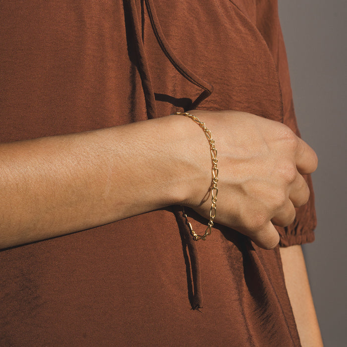 Gold-toned chain bracelet with linked oval segments worn on wrist.