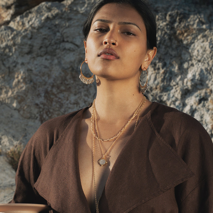 Gold-tone chain necklace with linked geometric pendant worn layered on model.